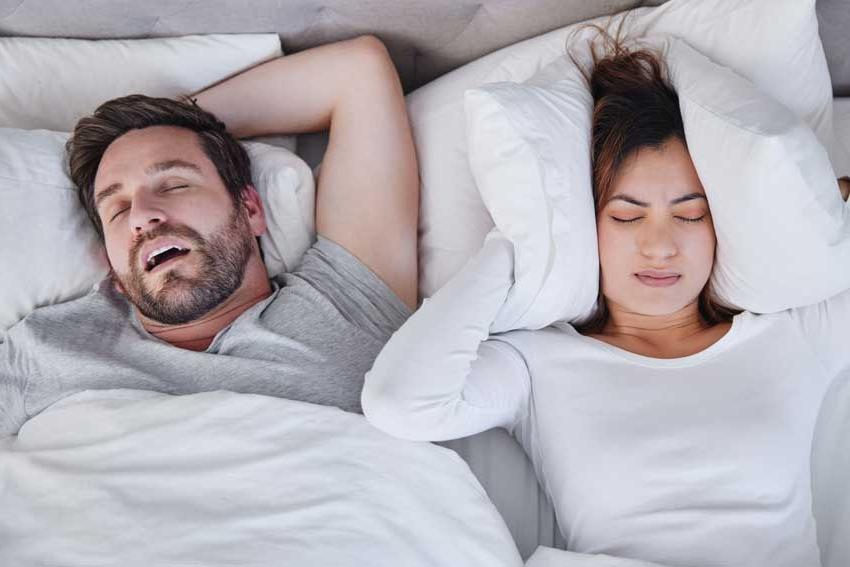 woman covering ears due to husband snoring